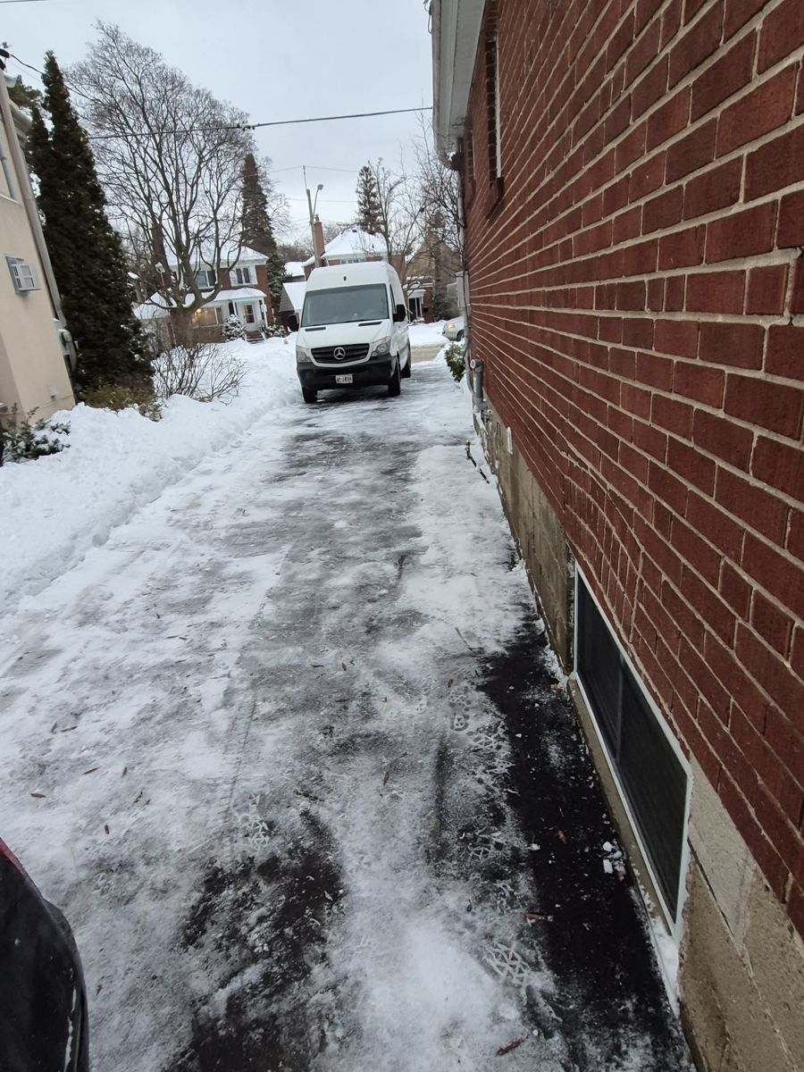 Long driveway beside a brick house cleared of snow and ice