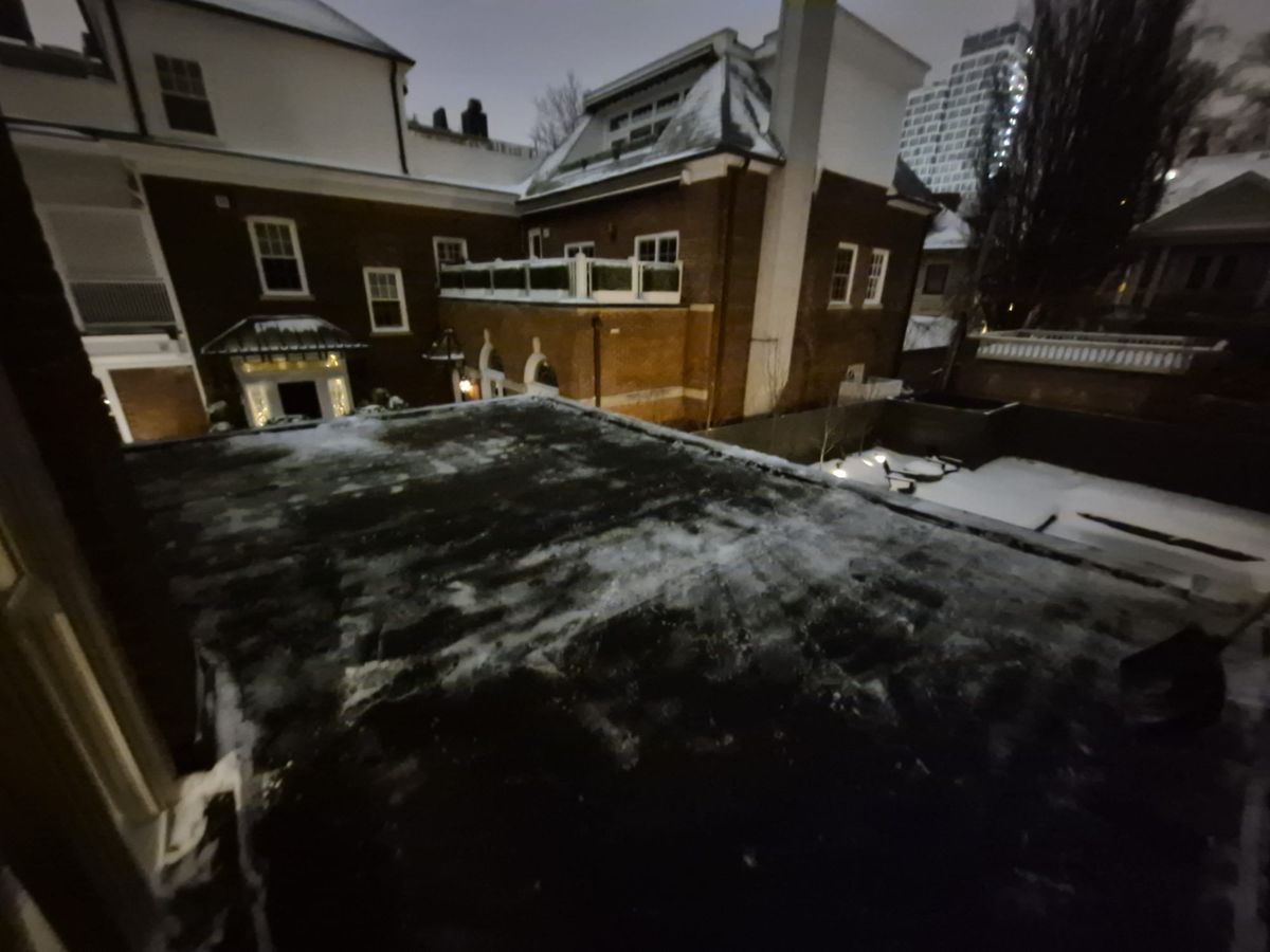 Flat roof cleared of heavy snow behind Toronto houses at night