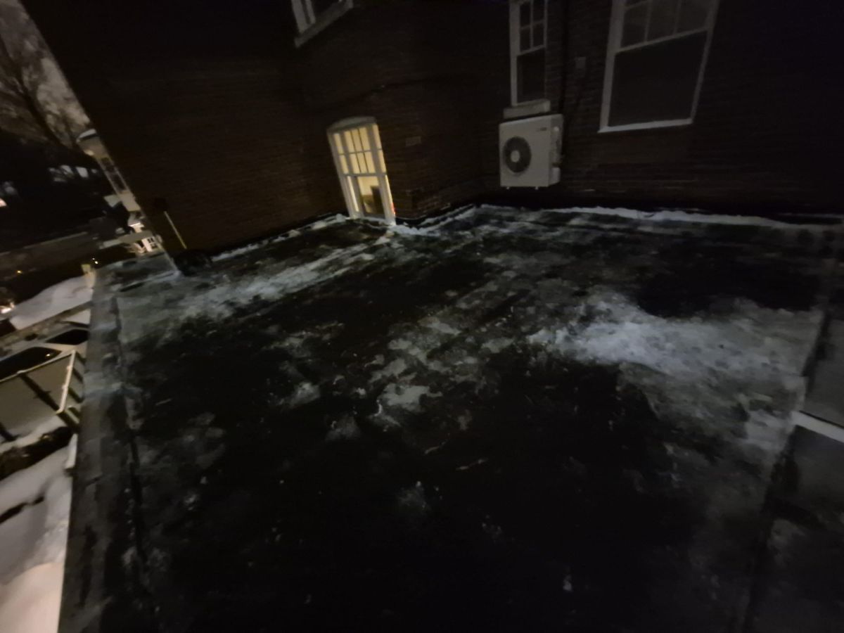 Rooftop deck outside a door cleared of snow at night