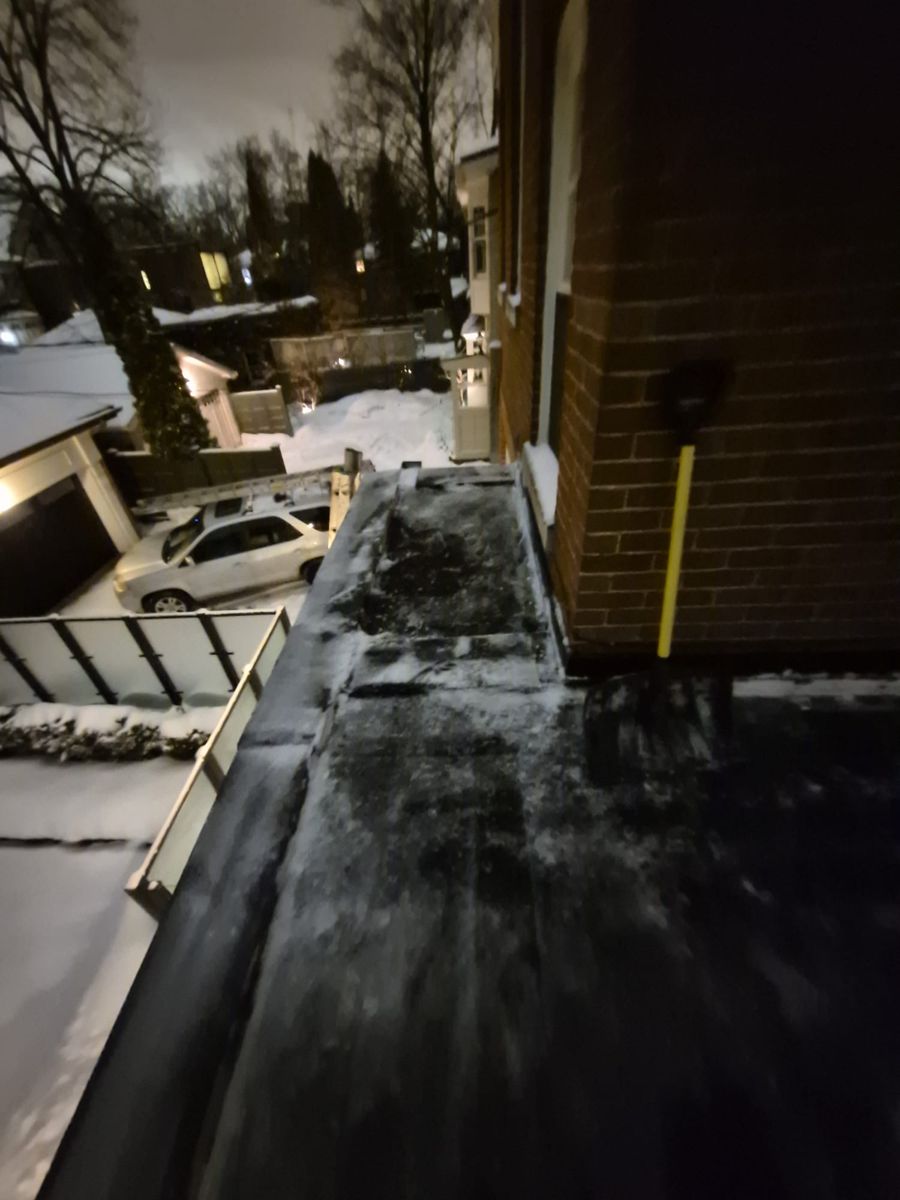 Narrow flat roof along a brick wall cleared with a snow shovel